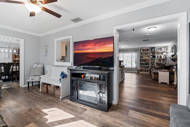 living room featuring hardwood / wood-style floors, ceiling fan, a textured ceiling, crown molding, and built in shelves