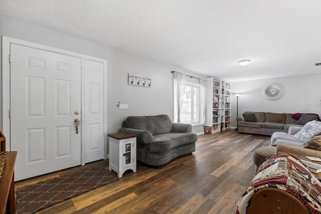 living room with a textured ceiling and dark wood-type flooring