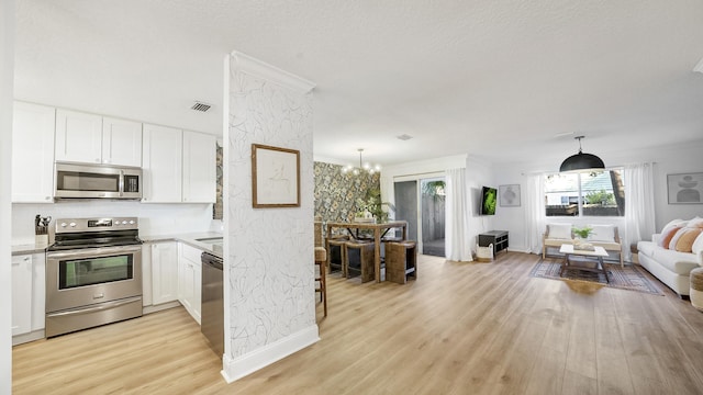 kitchen with visible vents, white cabinets, light wood-style floors, appliances with stainless steel finishes, and crown molding