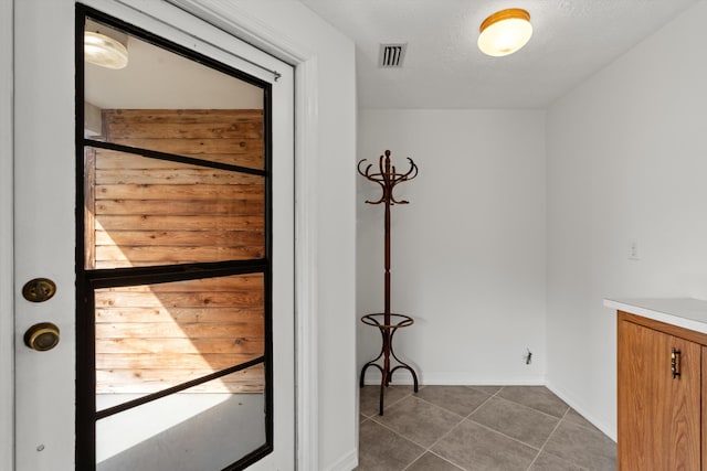 doorway to outside featuring dark tile patterned flooring and a textured ceiling