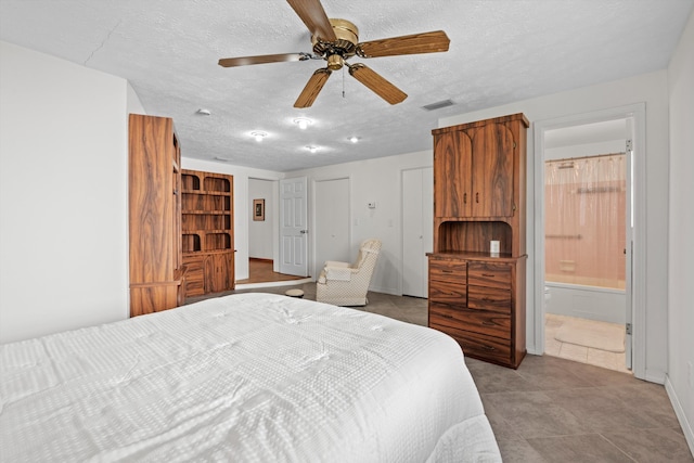 tiled bedroom with ceiling fan, connected bathroom, and a textured ceiling