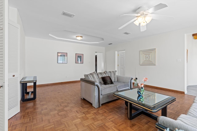 living room featuring parquet floors, ceiling fan, and a tray ceiling