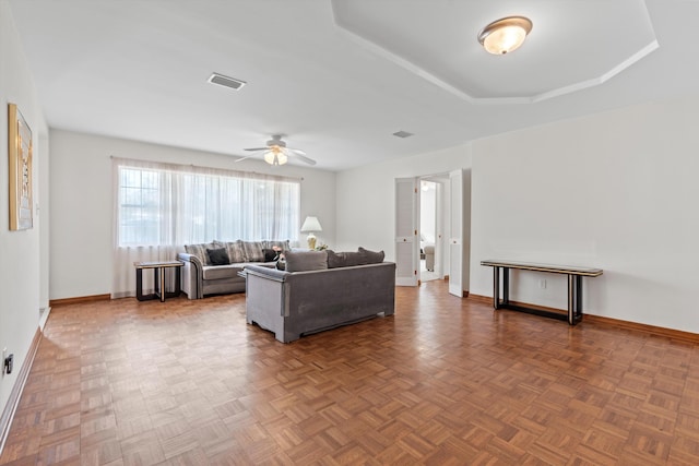 living room featuring parquet floors, ceiling fan, and a raised ceiling