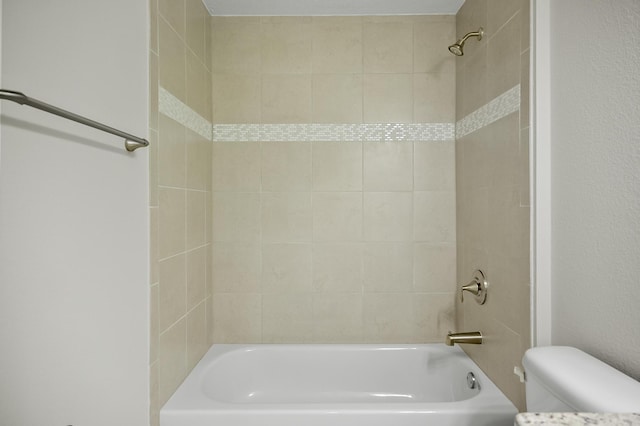 bathroom with tiled shower / bath combo and toilet