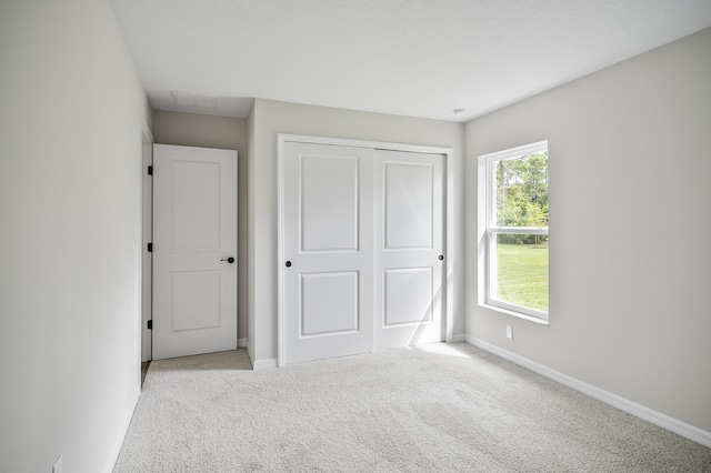 unfurnished bedroom featuring light colored carpet and a closet