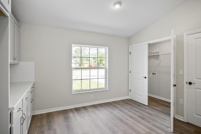 unfurnished bedroom featuring lofted ceiling, light wood-type flooring, and a closet