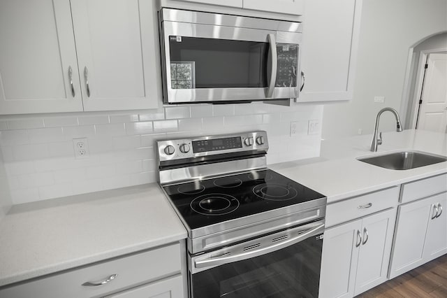 kitchen with sink, white cabinets, appliances with stainless steel finishes, and tasteful backsplash