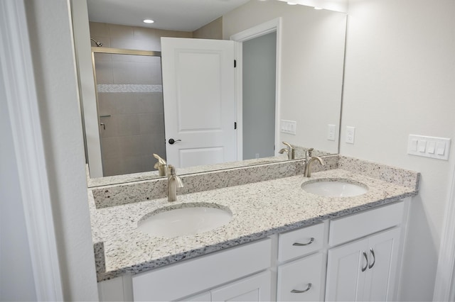 bathroom featuring a shower with shower door and vanity