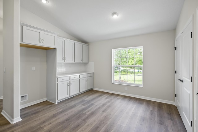 kitchen featuring lofted ceiling, white cabinets, decorative backsplash, and light hardwood / wood-style flooring