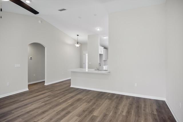 unfurnished living room featuring ceiling fan, vaulted ceiling, dark hardwood / wood-style flooring, and sink