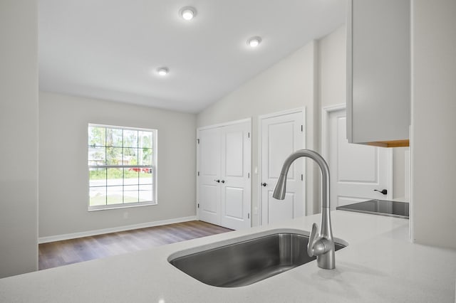 kitchen with lofted ceiling, sink, and light hardwood / wood-style flooring