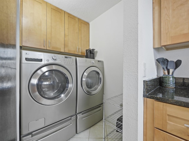 laundry area featuring washer and dryer, cabinets, light tile patterned floors, and a textured ceiling