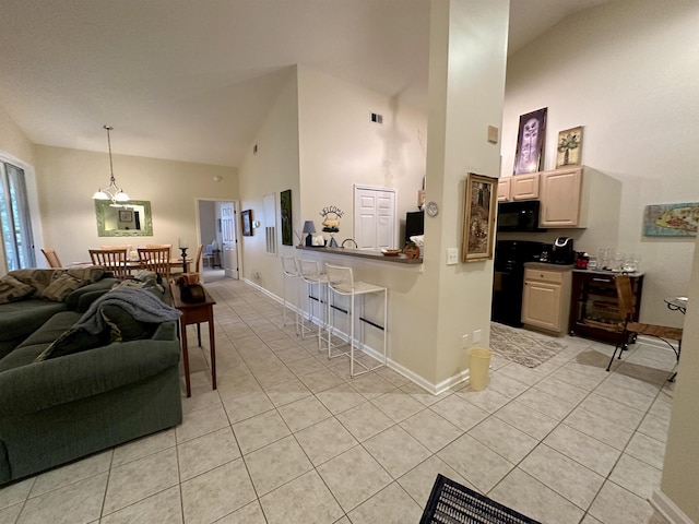 kitchen with a breakfast bar, black appliances, pendant lighting, light tile patterned floors, and high vaulted ceiling