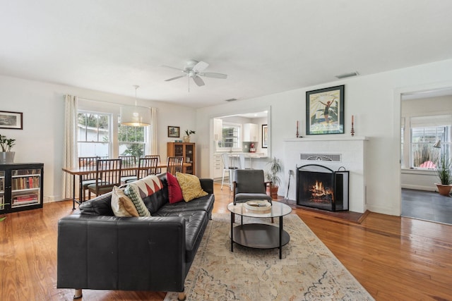 living room featuring a fireplace, wood-type flooring, and ceiling fan