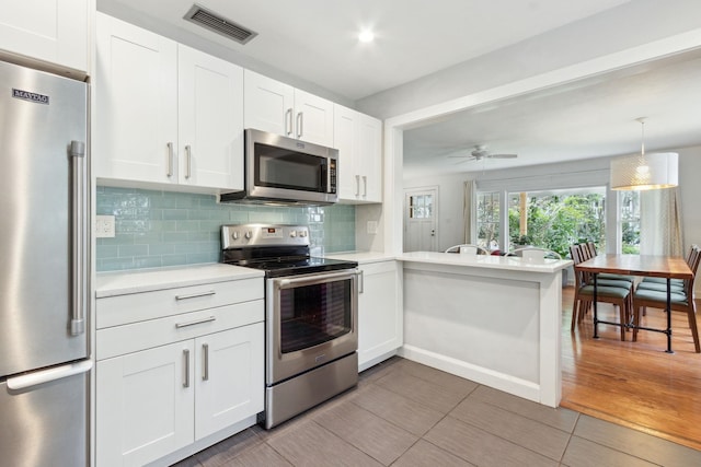 kitchen with backsplash, kitchen peninsula, ceiling fan, white cabinetry, and stainless steel appliances