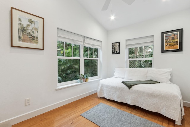 bedroom featuring multiple windows, hardwood / wood-style flooring, vaulted ceiling, and ceiling fan