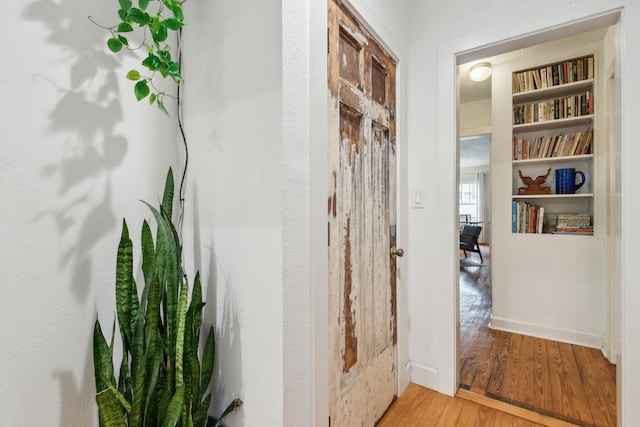 corridor featuring built in features and light hardwood / wood-style flooring