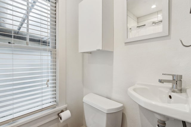 bathroom featuring plenty of natural light, toilet, and sink