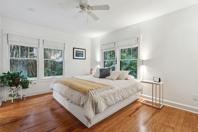 bedroom featuring multiple windows, hardwood / wood-style floors, and ceiling fan