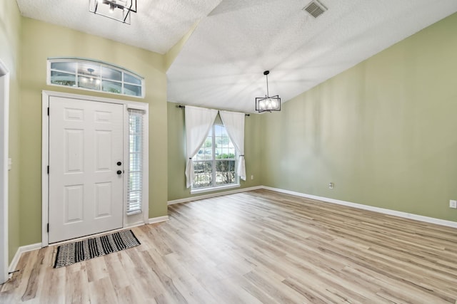 entrance foyer featuring a textured ceiling, a chandelier, and light hardwood / wood-style flooring