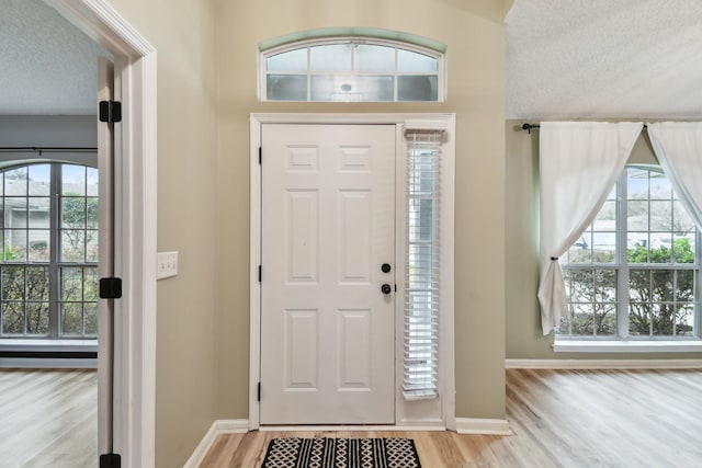 foyer entrance with a textured ceiling, wood finished floors, and baseboards