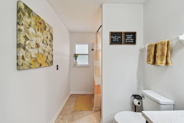 bathroom featuring vanity, toilet, tile patterned floors, and a textured ceiling