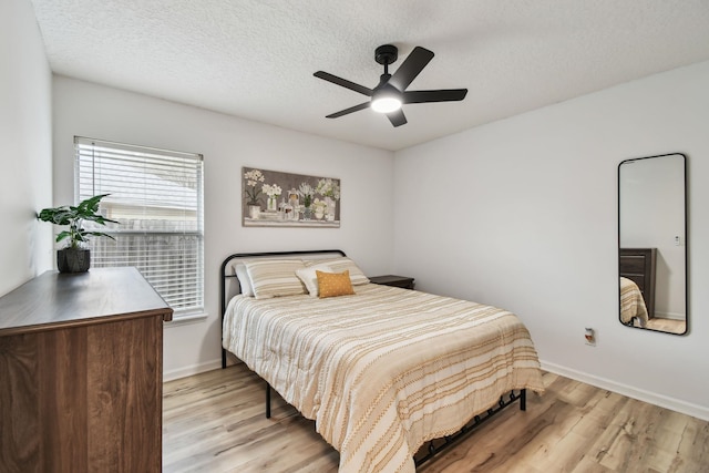 bedroom with light wood-style floors, ceiling fan, a textured ceiling, and baseboards