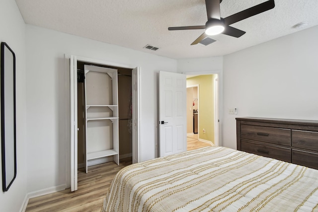 bedroom with a textured ceiling, light hardwood / wood-style flooring, a closet, and ceiling fan