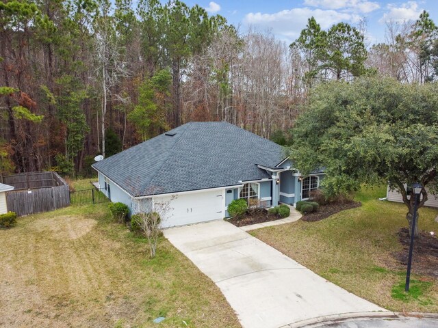 view of front of house with a shingled roof, concrete driveway, an attached garage, fence, and a front lawn