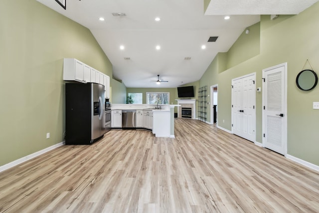 kitchen with white cabinets, appliances with stainless steel finishes, sink, kitchen peninsula, and a tile fireplace