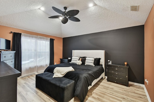 bedroom featuring visible vents, a ceiling fan, a textured ceiling, wood finished floors, and baseboards