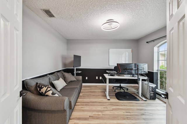 office with a textured ceiling, wood finished floors, and visible vents