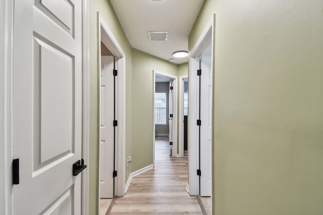 hall featuring light wood-style floors and baseboards