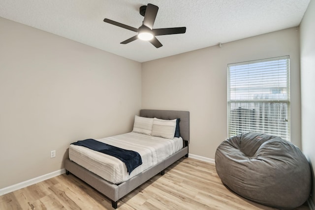 bedroom featuring light wood-type flooring, ceiling fan, a textured ceiling, and baseboards