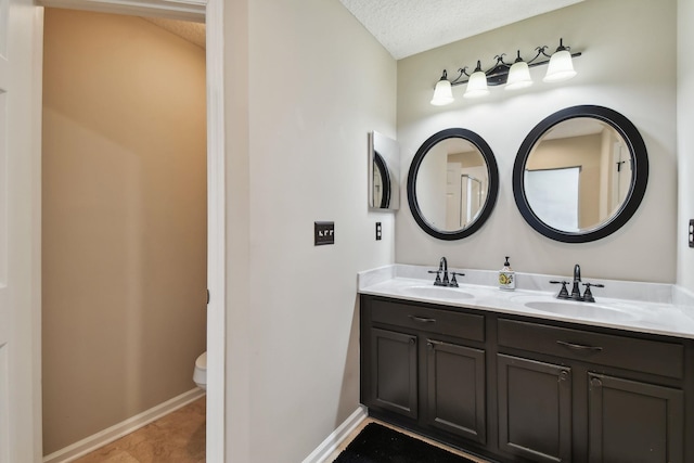 bathroom with toilet, a textured ceiling, tile patterned floors, and vanity