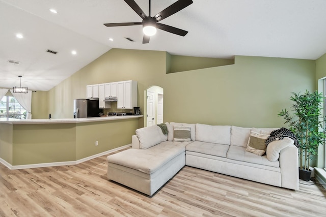 living room with ceiling fan with notable chandelier, light hardwood / wood-style flooring, and high vaulted ceiling