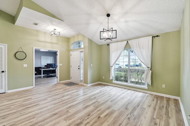 unfurnished dining area featuring visible vents, light wood-style floors, a textured ceiling, a chandelier, and baseboards