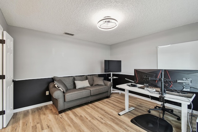 office with a textured ceiling, visible vents, and light wood-style floors