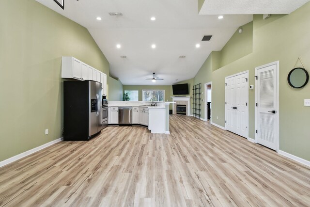 kitchen with vaulted ceiling, white cabinetry, sink, kitchen peninsula, and stainless steel appliances