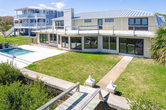 back of property featuring a fenced in pool, a patio area, a yard, and a balcony