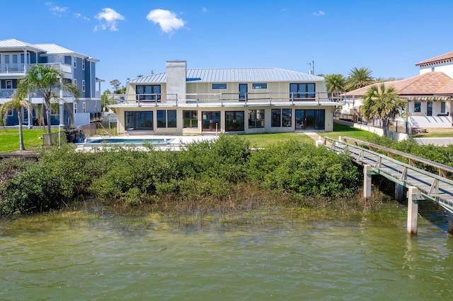 back of house featuring a water view, a balcony, and a swimming pool