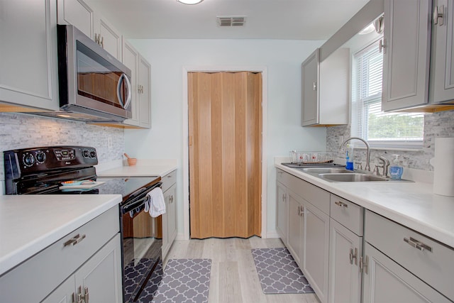 kitchen with sink, tasteful backsplash, black electric range, light hardwood / wood-style flooring, and gray cabinets