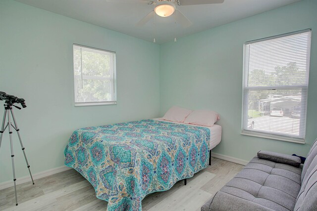 bedroom with ceiling fan, light hardwood / wood-style floors, and multiple windows