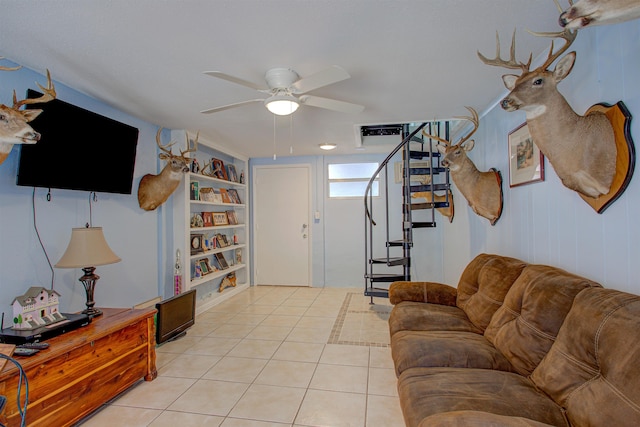 living room with ceiling fan, wooden walls, and light tile patterned floors