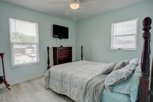 bedroom with ceiling fan, light hardwood / wood-style floors, and multiple windows