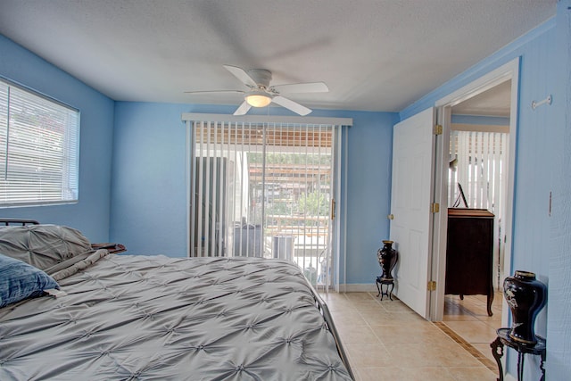 bedroom featuring ceiling fan, access to exterior, a textured ceiling, and multiple windows