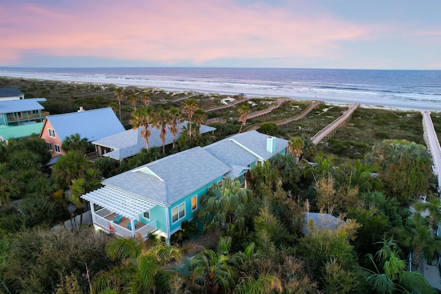 aerial view at dusk with a water view and a beach view