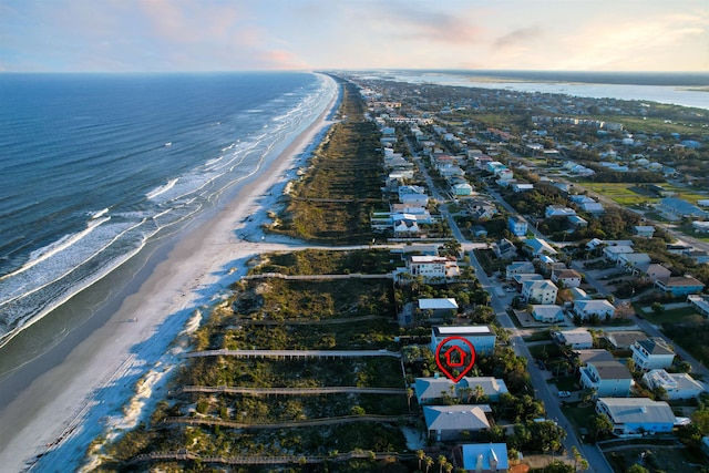 aerial view at dusk featuring a water view and a beach view