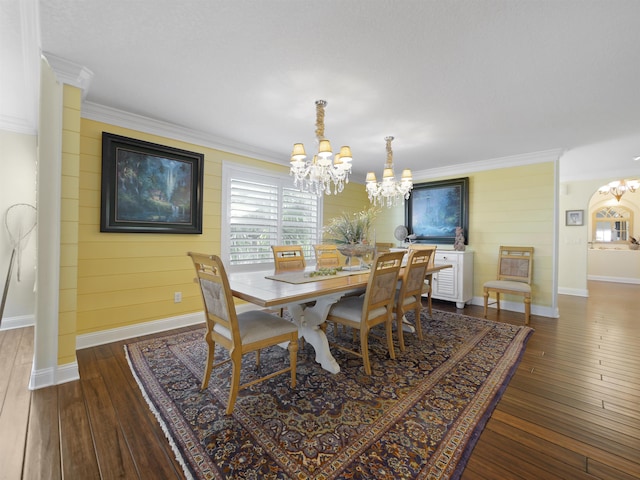 dining room featuring wood walls, ornamental molding, dark wood-type flooring, and a notable chandelier