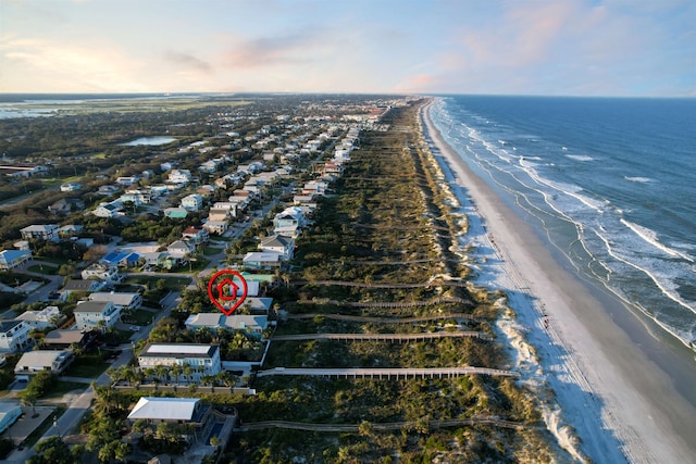 aerial view at dusk featuring a water view and a beach view